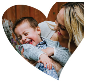 Heart-shaped framed close up photo of a woman and toddler giggling together.