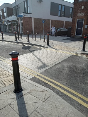 A dropped crossing across the road, with bollards on either side of the road