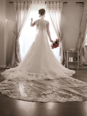 Bride in dress, holding flowers.