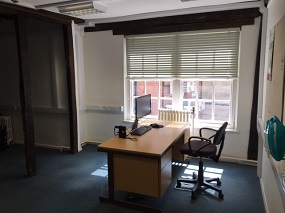 Desk by a window, with a computer monitor sat on the desk