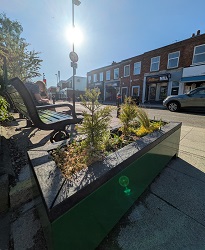 New green planters positioned next to a new bench, looking towards some of the shops on Acomb Front Street