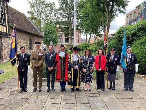 A line of people dressed in civic, military and associated forces uniform.