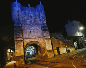 An historic gateway on York's city walls is lit up in blue and yellow lights.