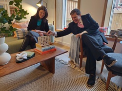 A woman sits on a sofa and a man in a chair