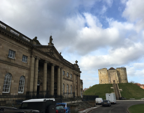 A large stone building with columns stands next to an earth mount with a tower atop