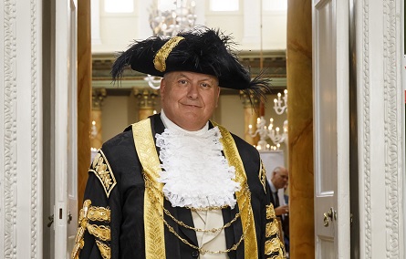 Head and shoulders of a man in black, white and gold mayoral dress
