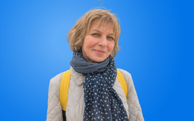 Health Trainers - Woman wearing coat, scarf and backpack, smiling