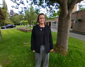 Woman stands next to a tree in front of a crematorium