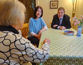 two councillors chat to a woman at her dining table