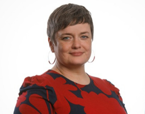 A woman in a black and red top smiles to camera