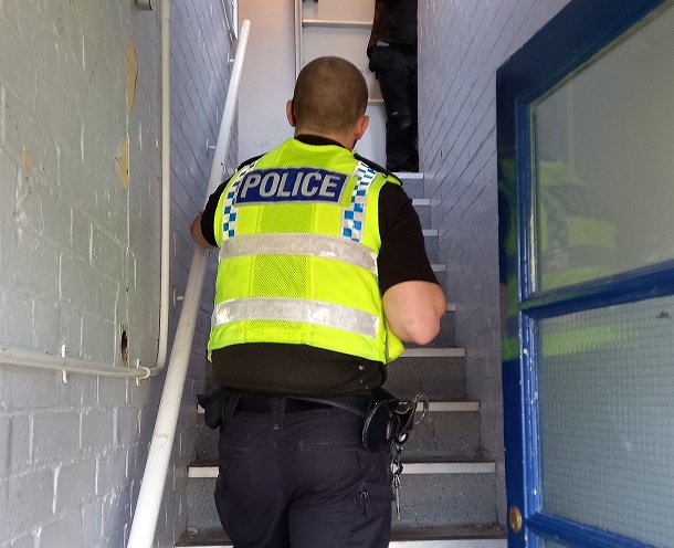 A uniformed police officer walks up a staircase