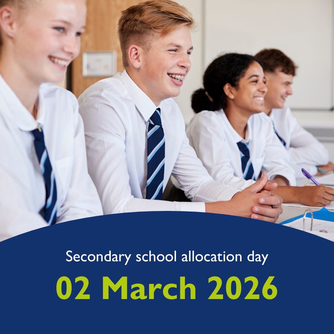 Photo of school children wearing white shirts and ties, sat at a long table