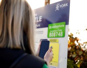 Image of a sign and a person holding up a phone
