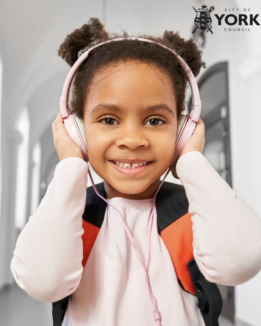 Young girl wearing headphones with her hands over her ears