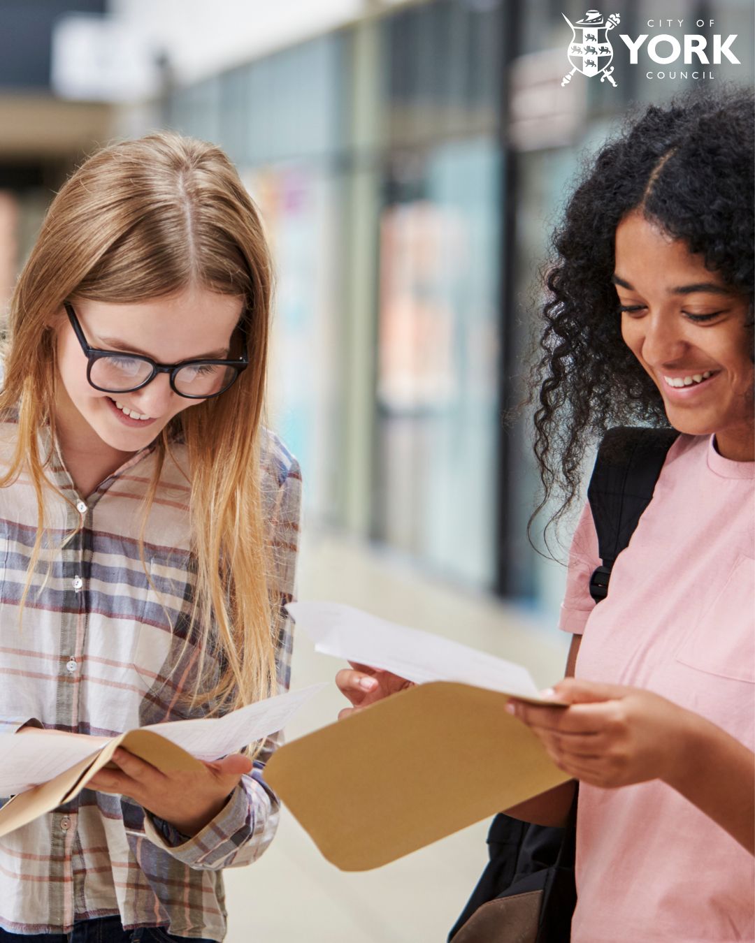 Two teenage students opening envelopes with exam results in