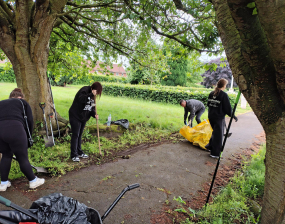 A group of people work to tidy a path and grass