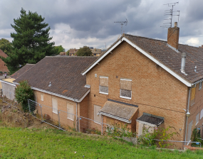 A boarded up building with grass in front