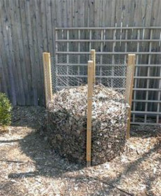 A composter made from wooden posts and chicken wire.