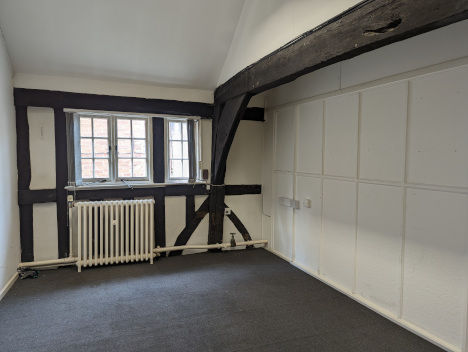 Inside the second floor office of Kings Court, the timber frame of the building is visible around a window and radiator as well as along the ceiling