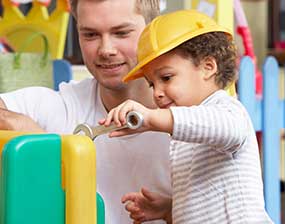 A man helping a young boy to play with construction toys