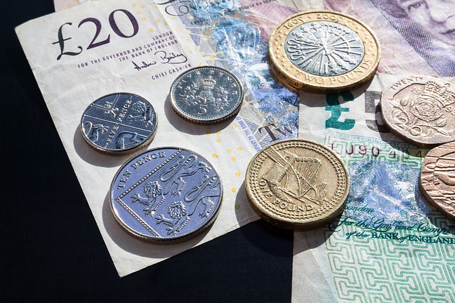 Various coins of pound sterling on top of a &pound;20 and &pound;5 banknotes