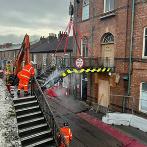 A photograph showing Queen Street slip road and construction workers removing the York RI footbridge.