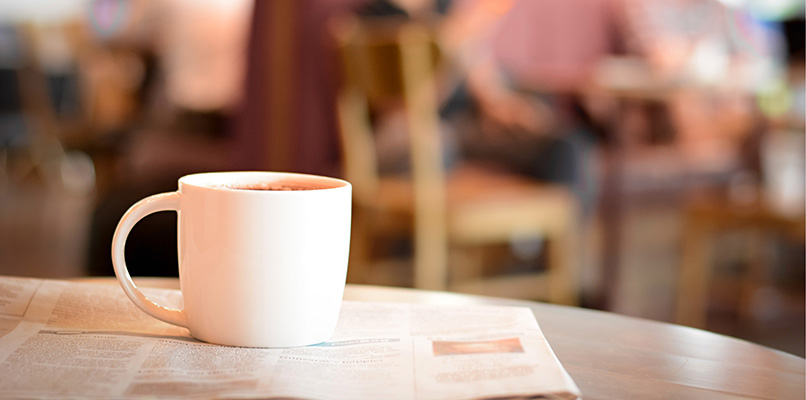 A cup of coffee, resting on a table, in a public caf&eacute;.