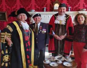 Four people: two in civic robes, one in veteran's uniform and a woman in red trousers