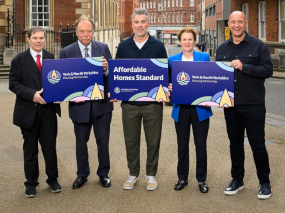 A group of five people hold posters announcing the new affordable homes standard