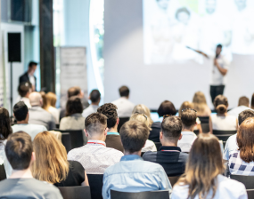 A speaker gives a presentation to a room full of people
