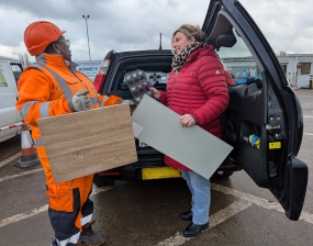 A photo of an operative at Hazel Court HWRC stood alongside and helping a resident