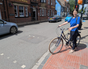 Cllr Jenny Kent stood, holding a bike, at a junction in York's city centre