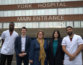 A group of five people, including two in medical uniforms, stand outside York Hospital's main entrance. The mood is professional and welcoming.