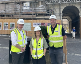 A photo of three representatives stood in front of the Mansion House