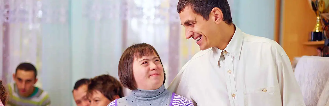 A young woman smiles as she looks up into the face of her carer.